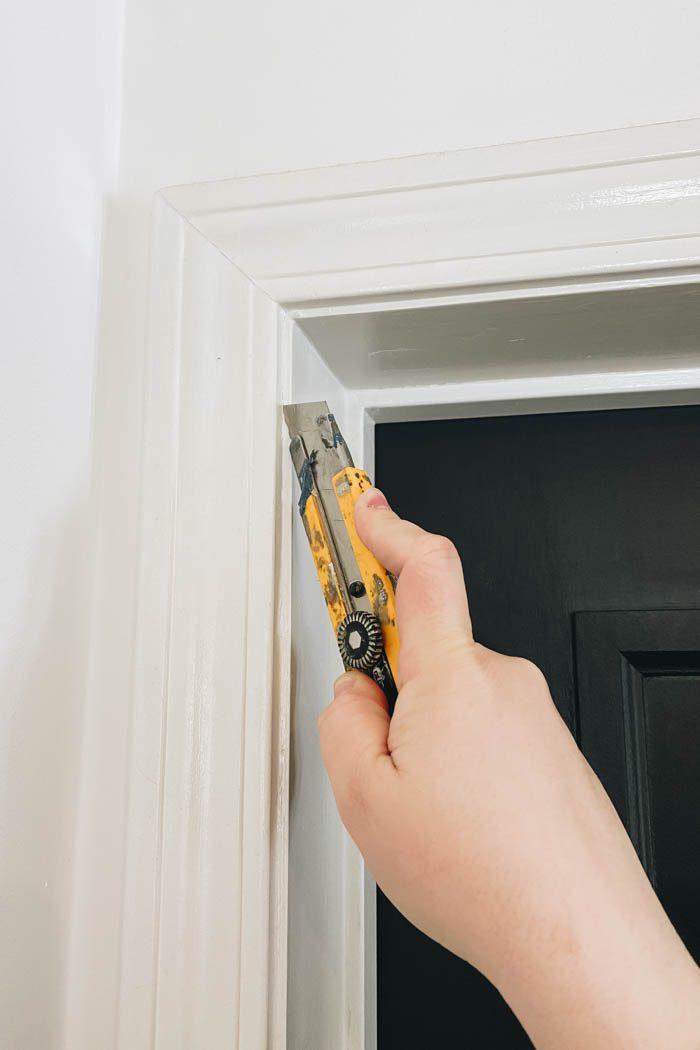 using a utility knife to score edge between moulding and casing